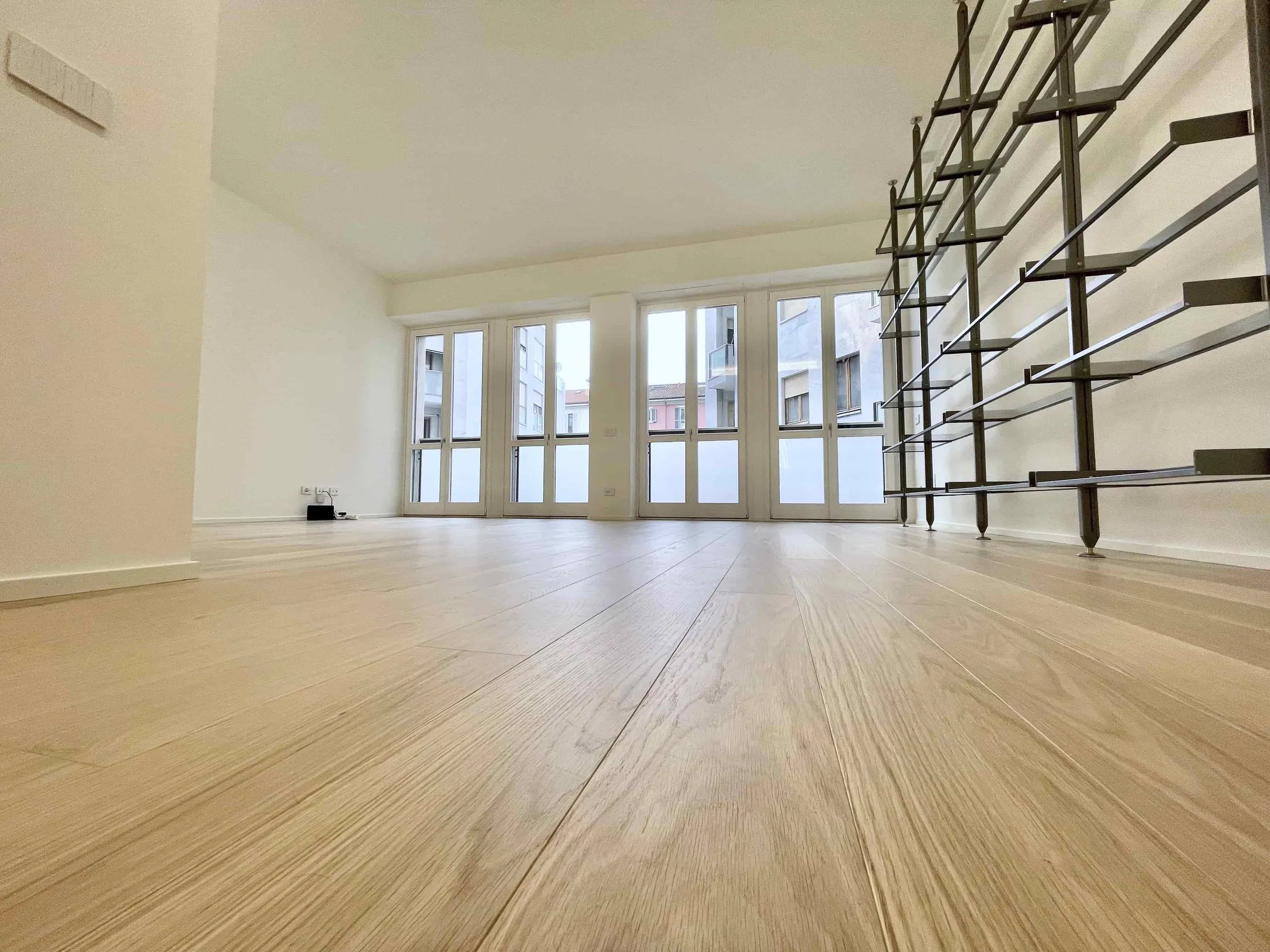 Soggiorno ristrutturato con parquet in rovere, vetrate e scala in metallo, lavoro CREACOS a Milano